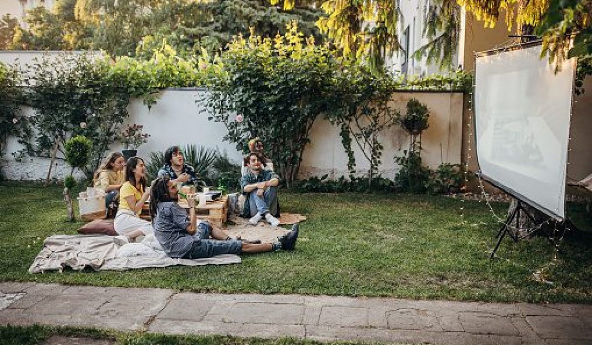 Friends watching movie on the video projector in the backyard garden