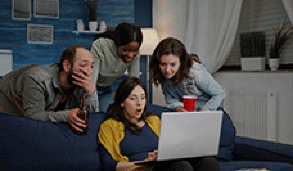 multiethnic-friends-watching-interesting-comedy-movie-laptop-computer-relaxing-couch-drinking